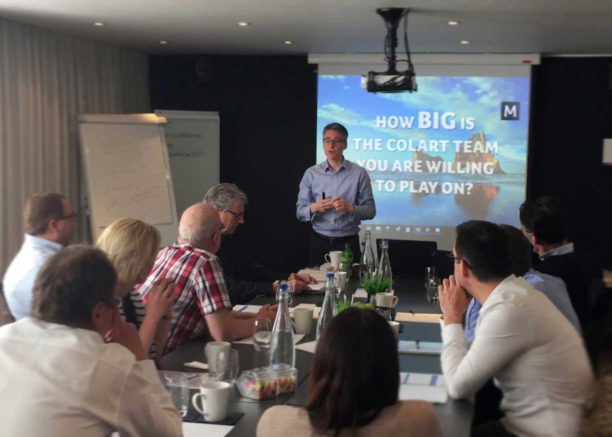 Paul Barnard facilitating an in-person workshop with a team seated around a meeting-room table