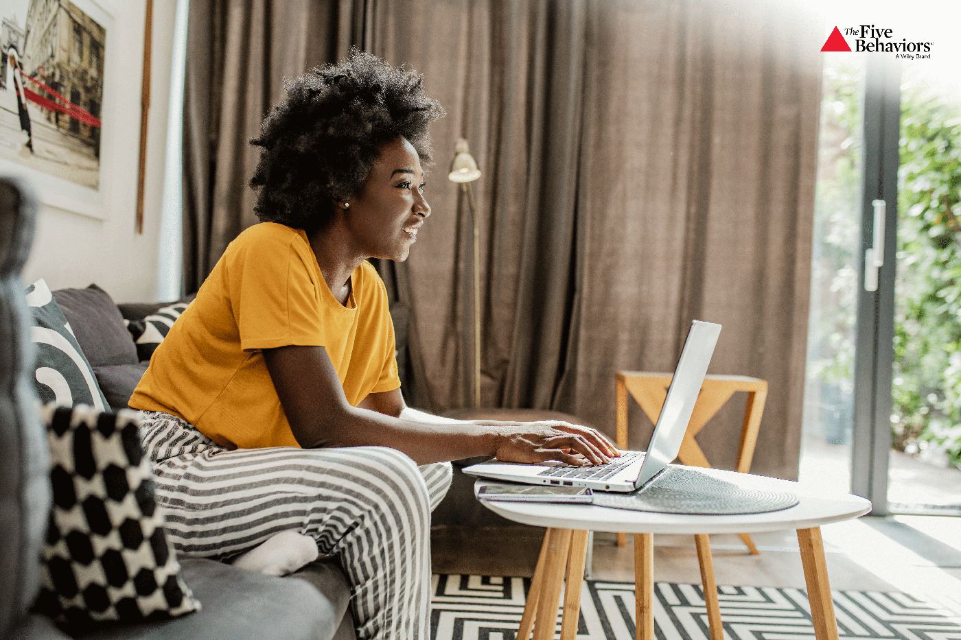 A person working thoughtfully on a laptop at home